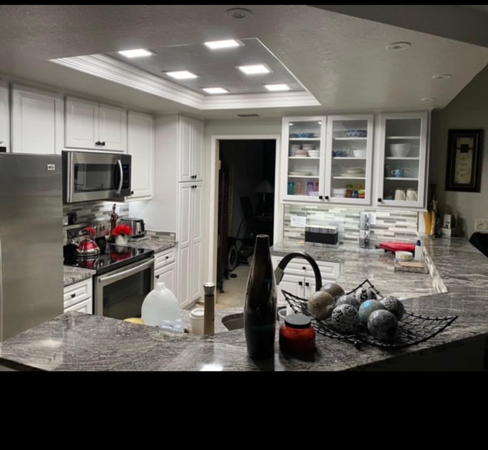 Modern kitchen with white cabinetry, granite countertops, and bright recessed lighting.