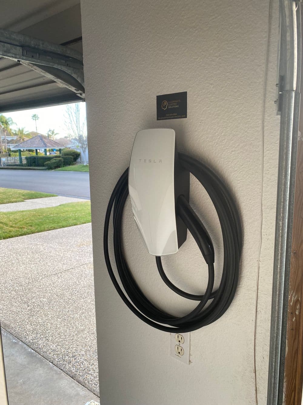 Tesla Wall Connector mounted on garage wall with charging cable neatly coiled.