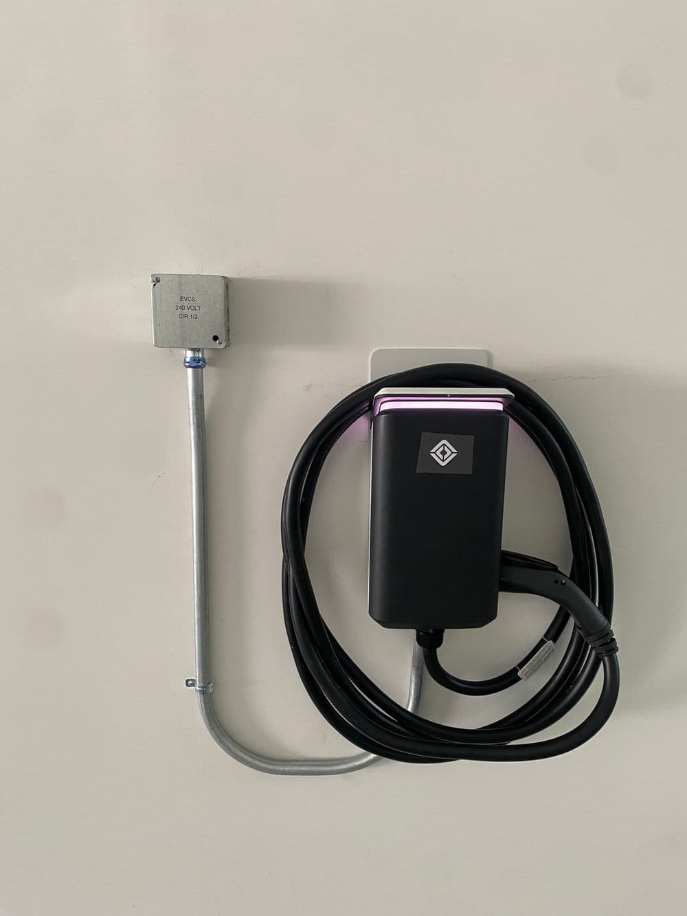 Electric vehicle charging station mounted on a wall with a coiled charging cable.