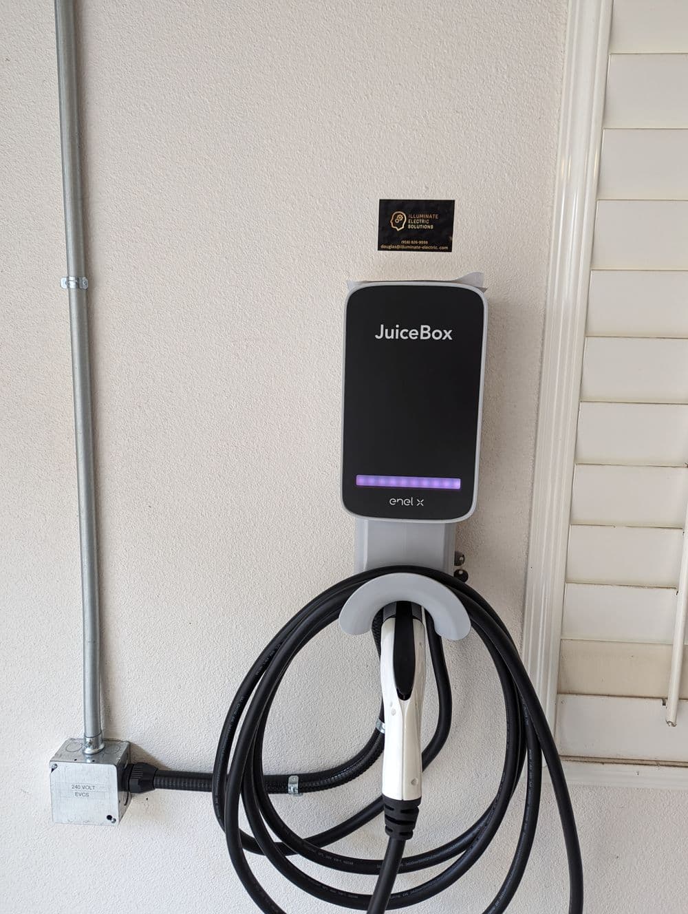 JuiceBox electric vehicle charger mounted on wall with charging cable hanging.