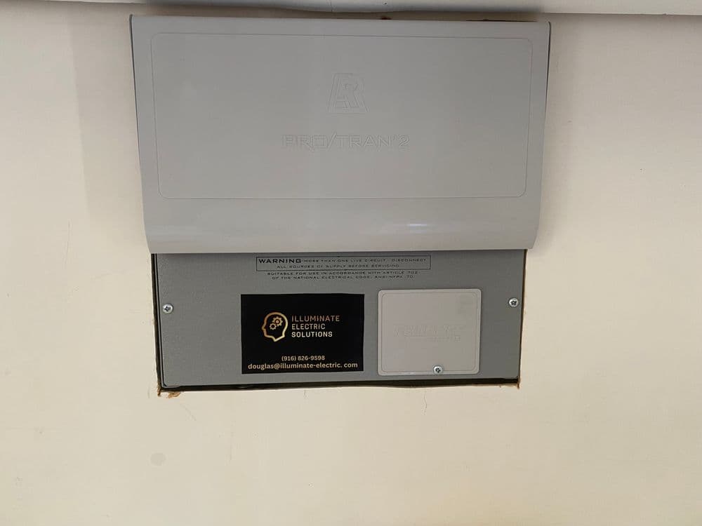 ProTran2 transfer switch mounted on wall with Illuminate Electric Solutions contact information.
