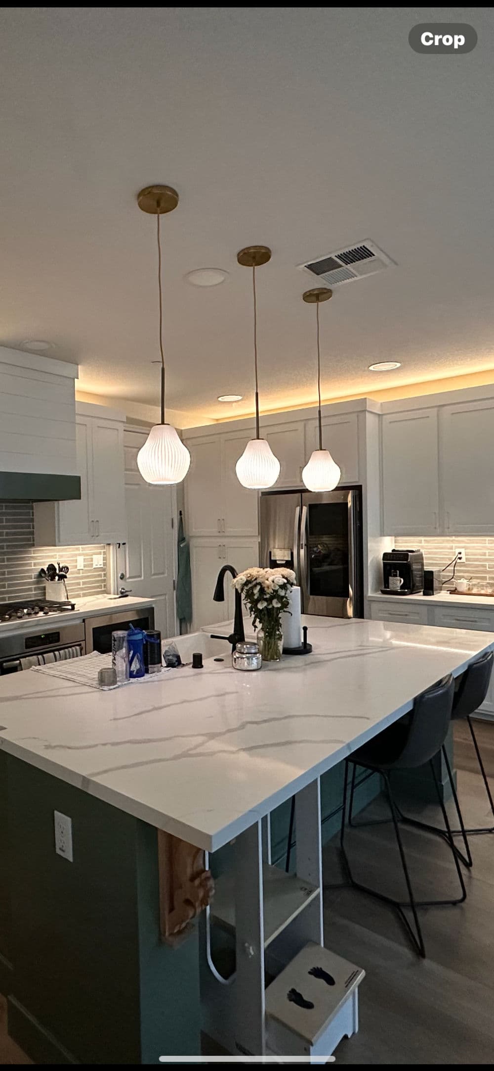 Modern kitchen with white cabinets, pendant lights, and a large island with flowers.