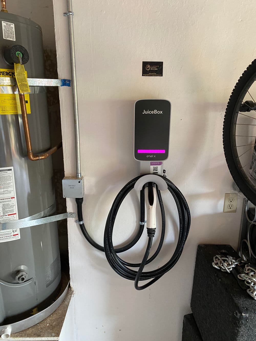 Wall-mounted JuiceBox EV charger with cables, located in a garage beside a water heater.
